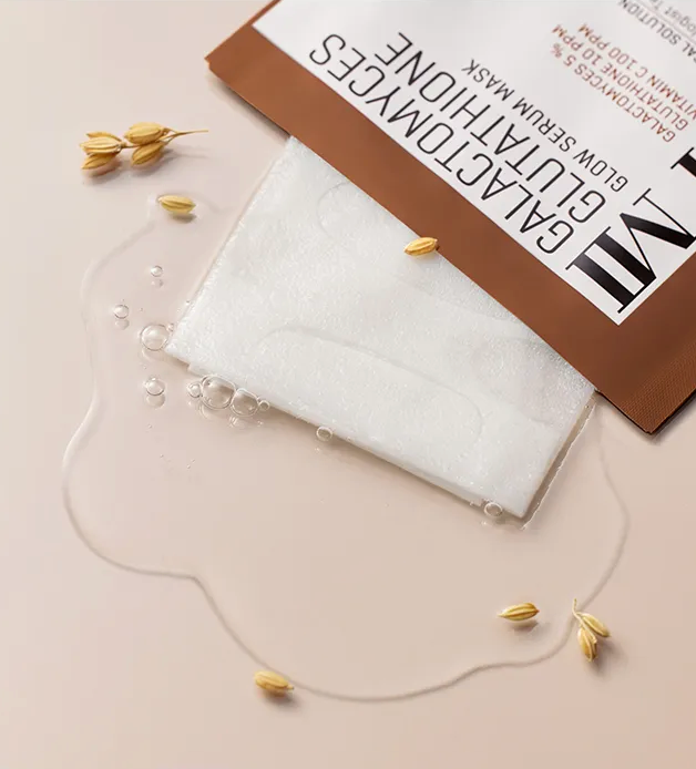 Sheet mask on a beige surface with a brown box labeled 'GALACTOMYCES' in the background.