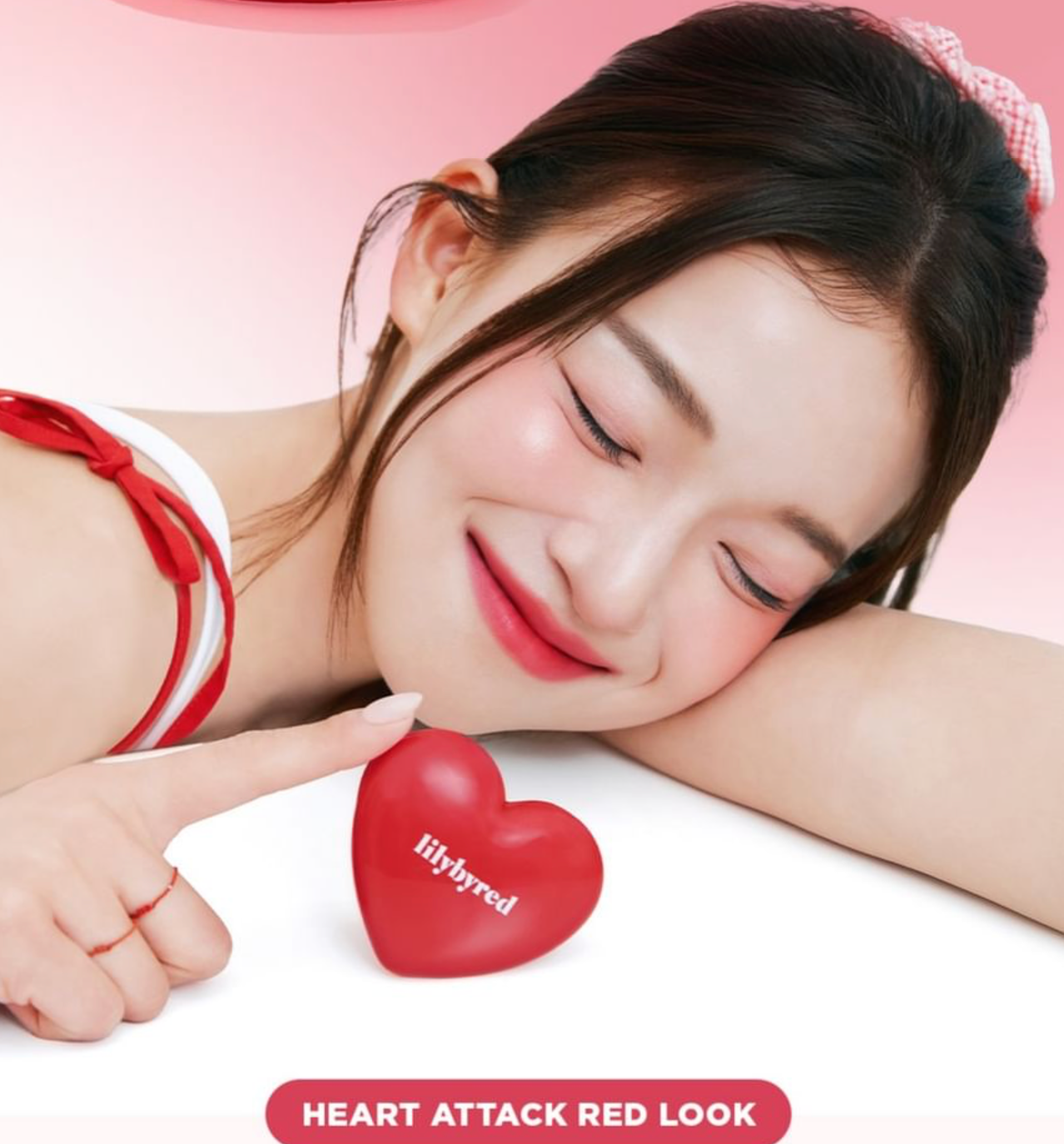 Woman holding a red heart-shaped product with 'lilybyred' branding against a pink background