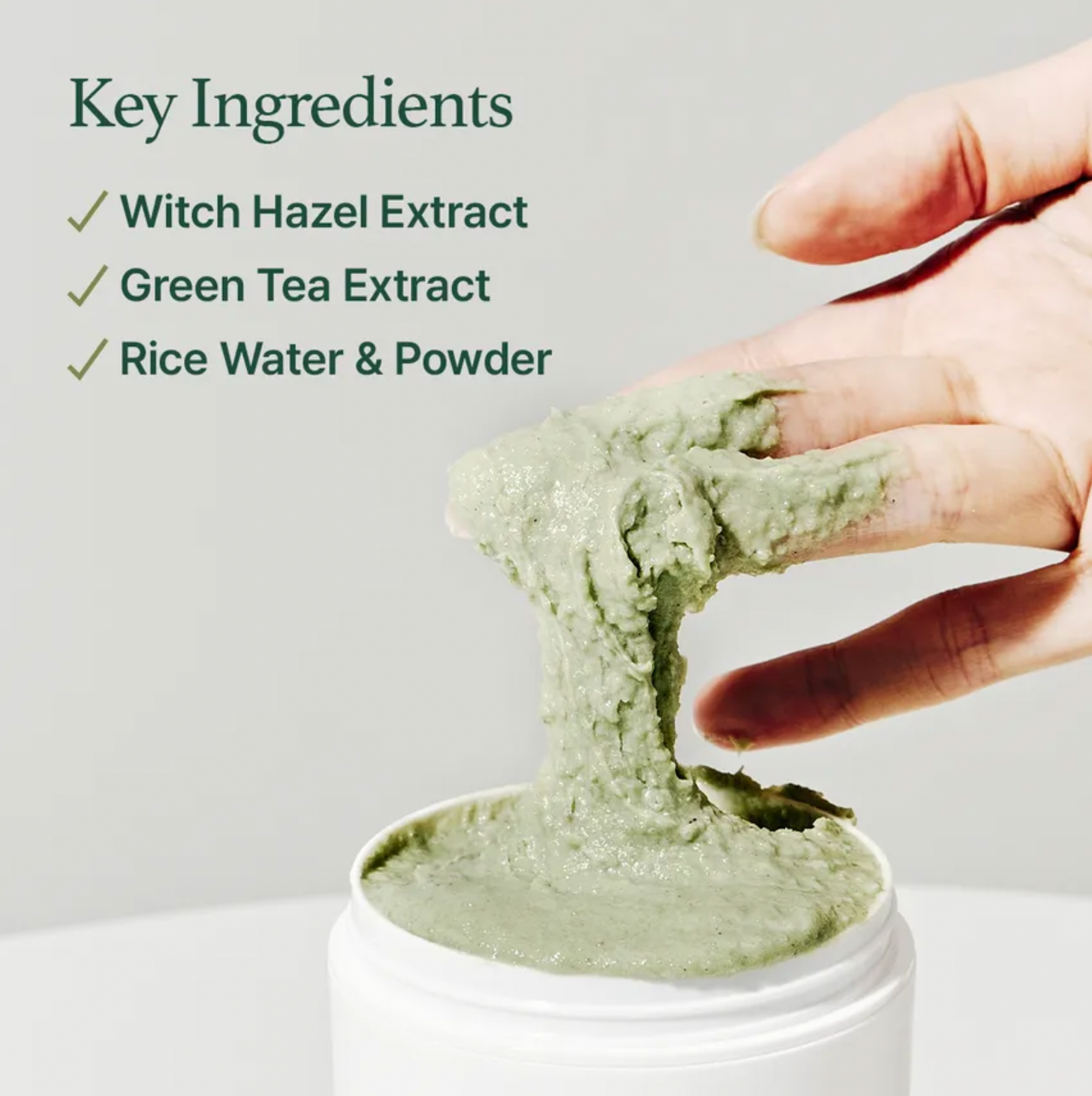Green clay mixture on a hand with a container below, labeled key ingredients including witch hazel extract, green tea extract, and rice water & powder.