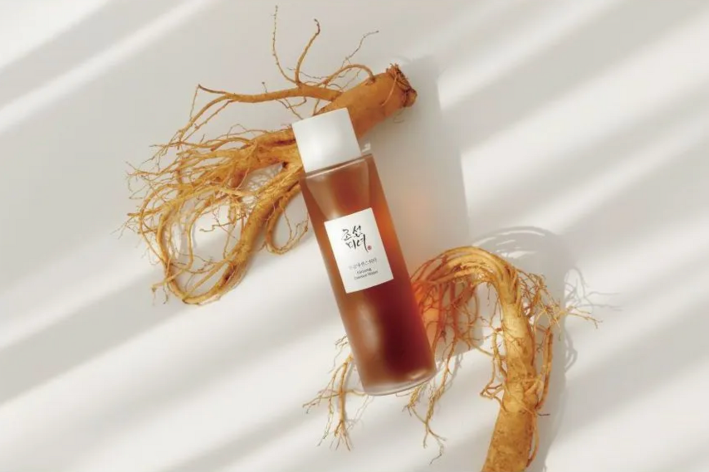 Skincare bottle with a ginseng root on a white background