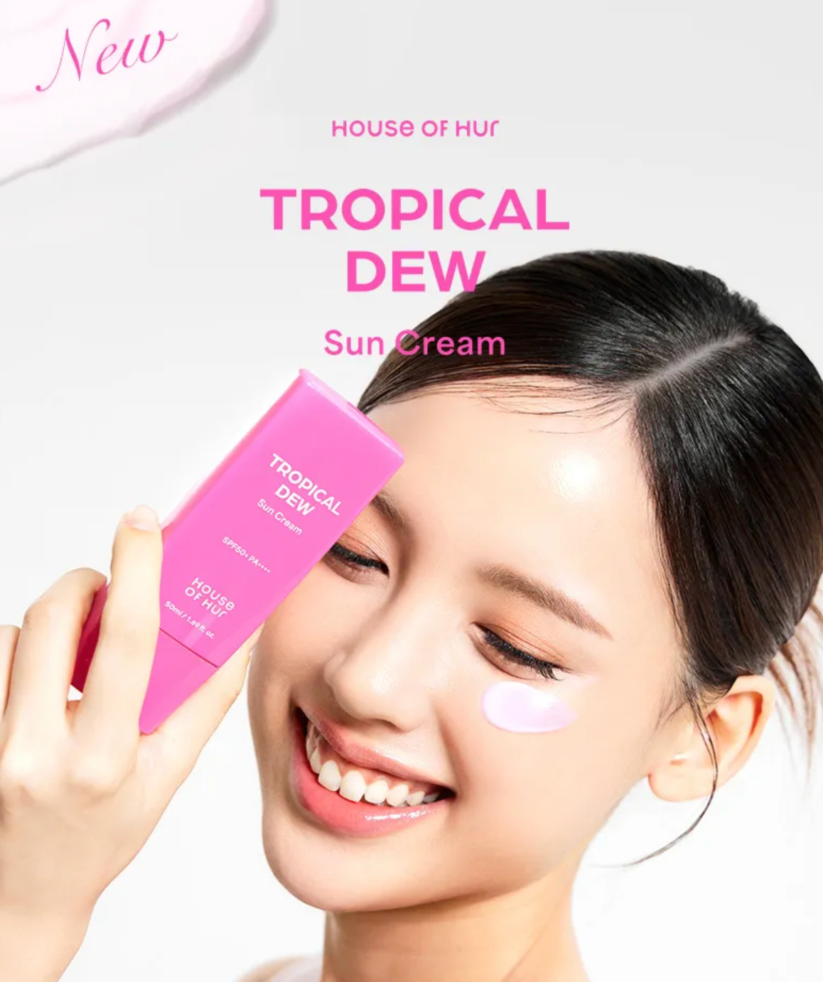Woman applying tropical dew sun cream to her face with a pink tube in the background