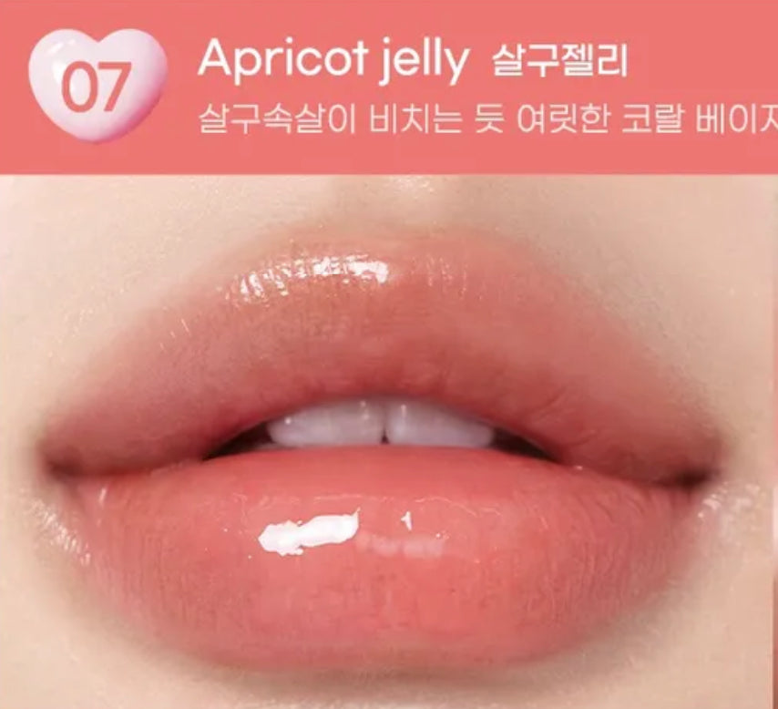Close-up of lips with apricot jelly lip gloss on a pink background