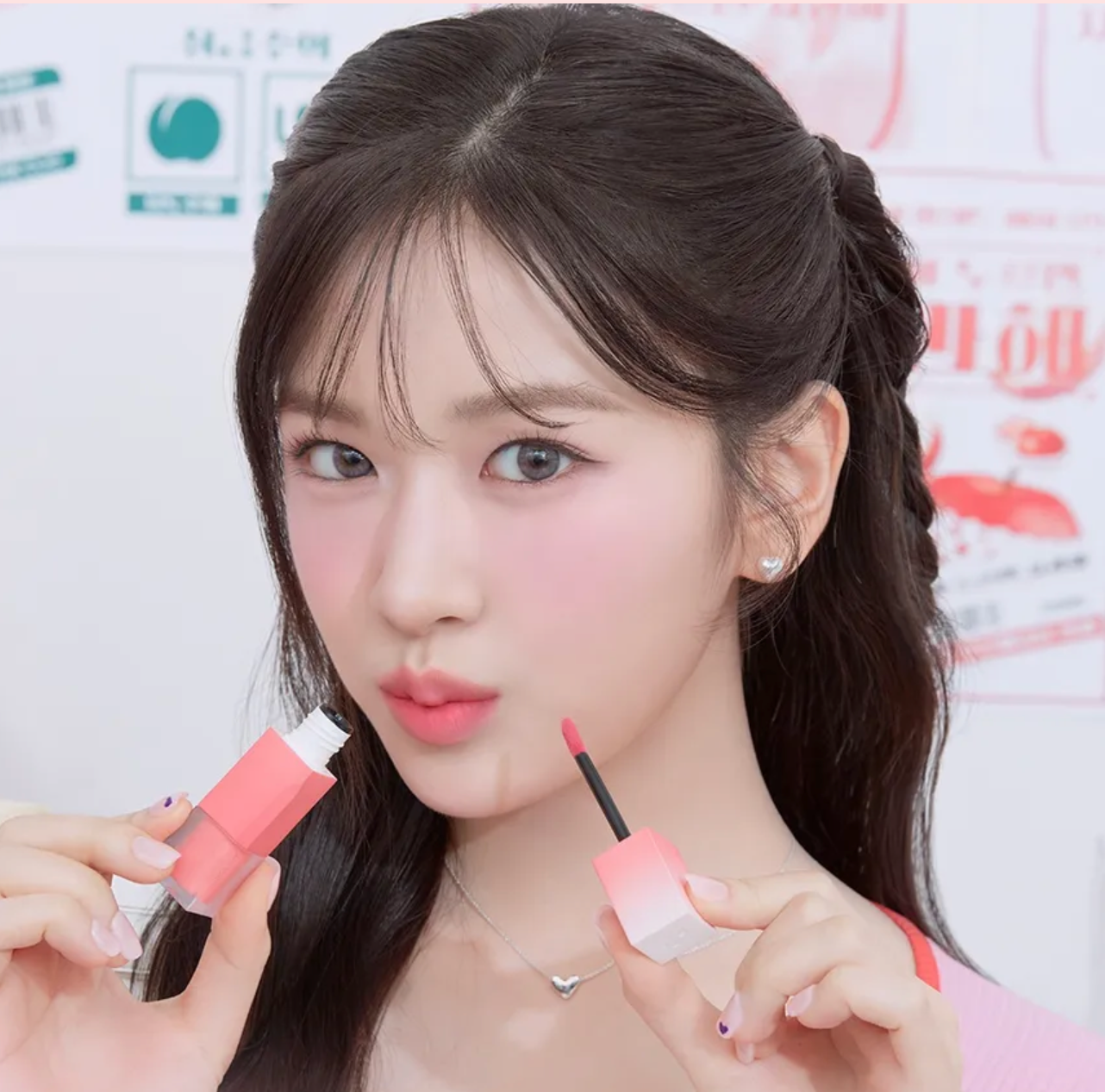 Woman holding two lip products with a blurred background