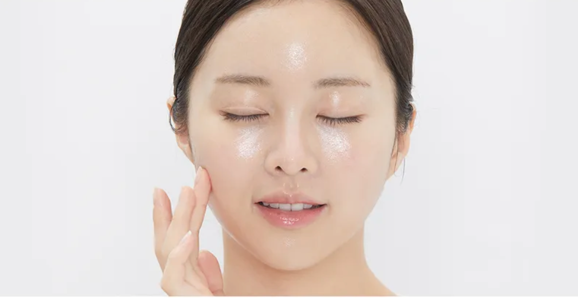 Woman applying a skincare product to her face with a white background