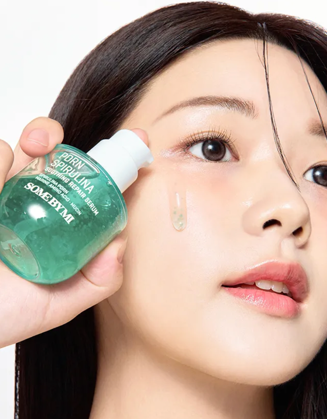 Person holding a bottle of SOMEBYMI skincare product near their face