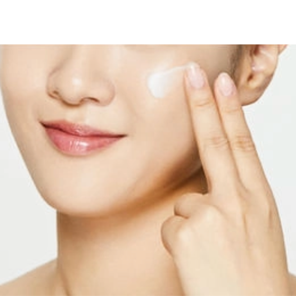 Person applying cream to their face with a neutral background