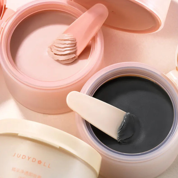 Close-up of cosmetic jars with applicators on a light pink background