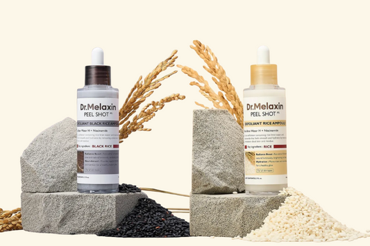 Two bottle serum on rocks with white and black rice grains on bottom.