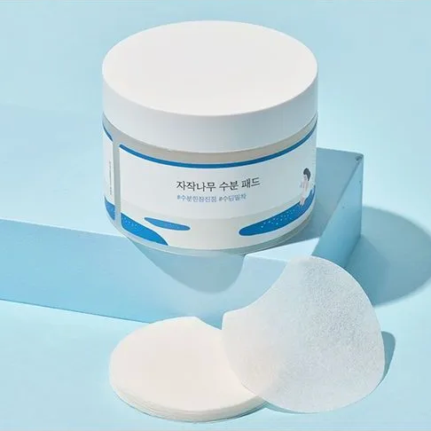 Cosmetic jar with two pads on a light blue background