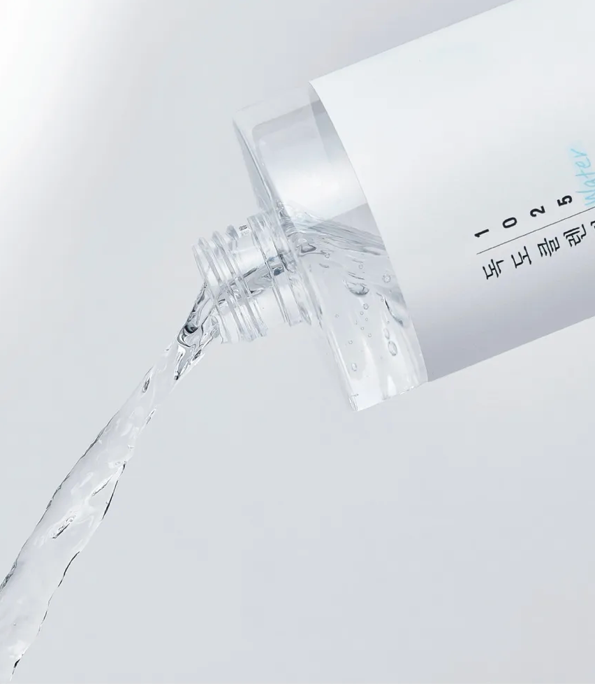 Clear dropper bottle with liquid being dispensed on a light gray background
