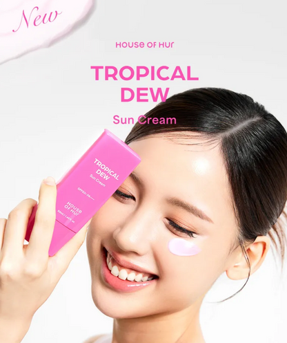 Woman applying tropical dew sun cream to her face with a pink tube in the background