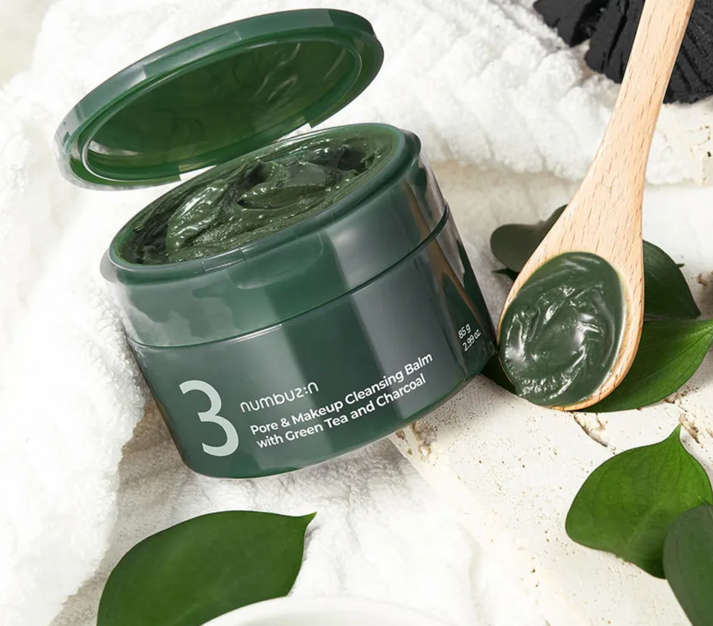 Green balm container with a wooden spoon on a white background