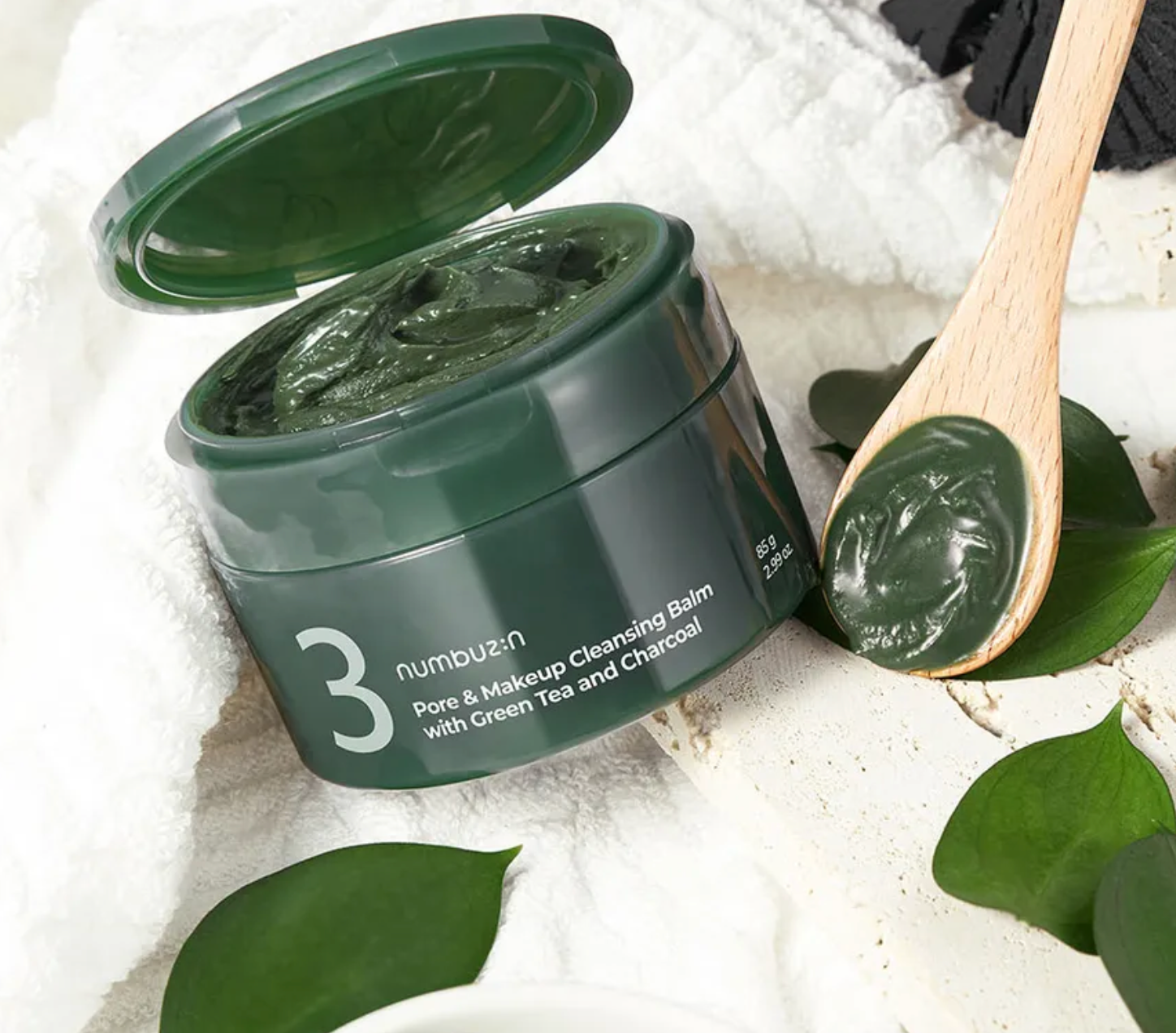 Green balm container with a wooden spoon on a white background