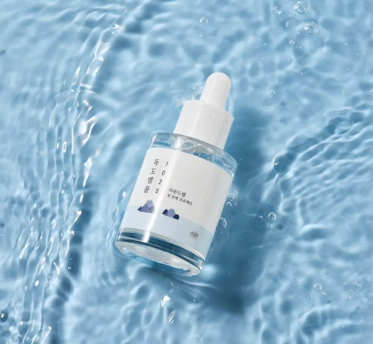 Skincare dropper bottle on water with a blue background