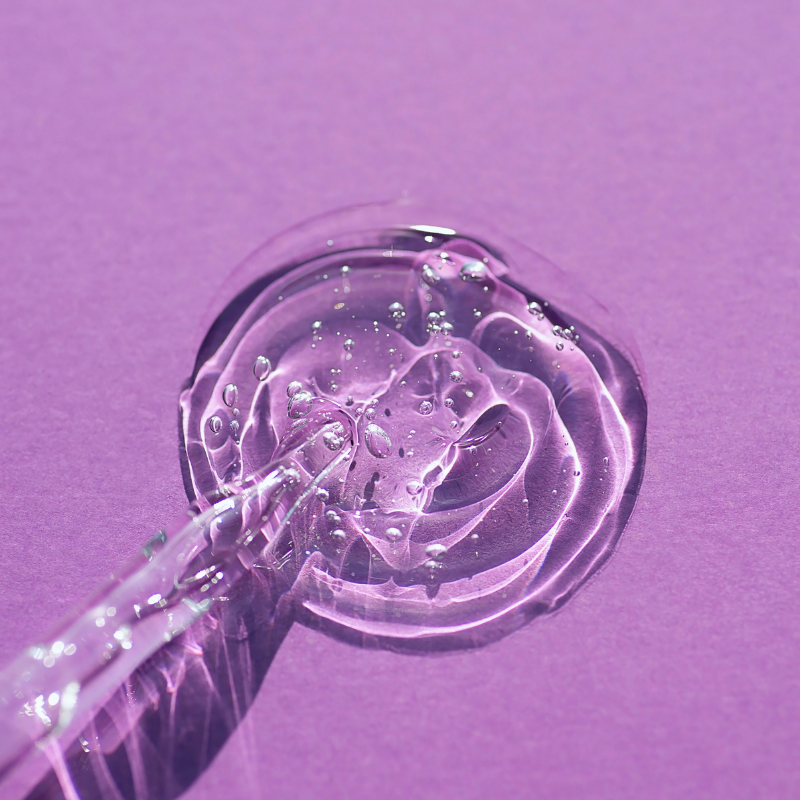 Clear gel-like substance on a applicator against a purple background